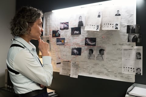 Detective studying crime evidence board with focused expression