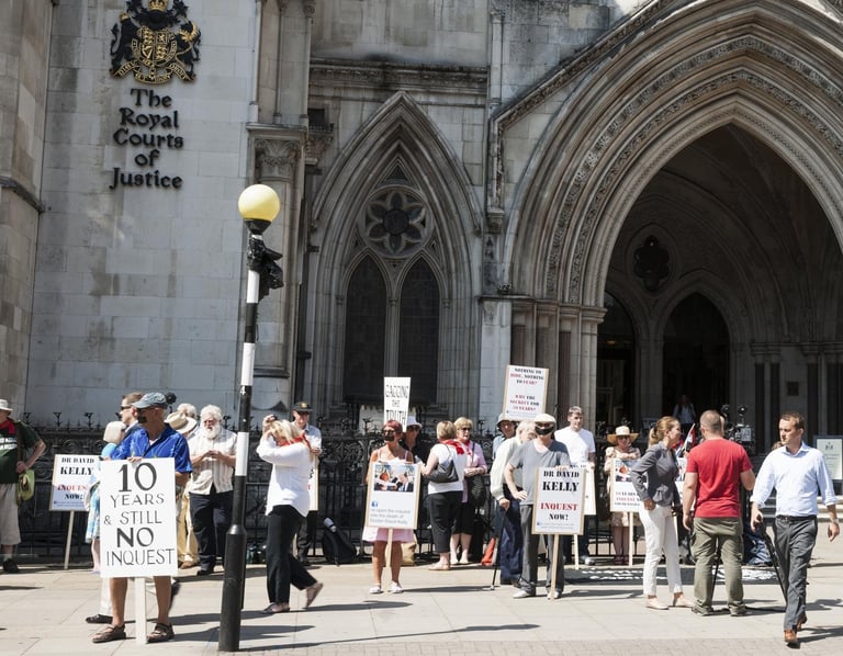 Protesters holding signs outside the Royal Courts of Justice building with gothic architecture